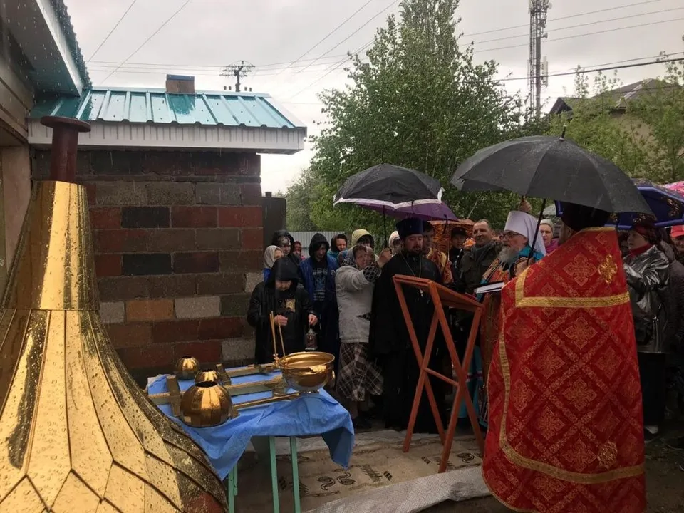 Митрополит Никон и духовенство освящают золочёные купола и кресты на улице под дождём
