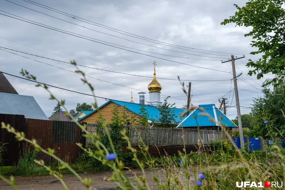 Небольшой храм с голубой кровлей и золотым куполом виден из-за заборов частных домов
